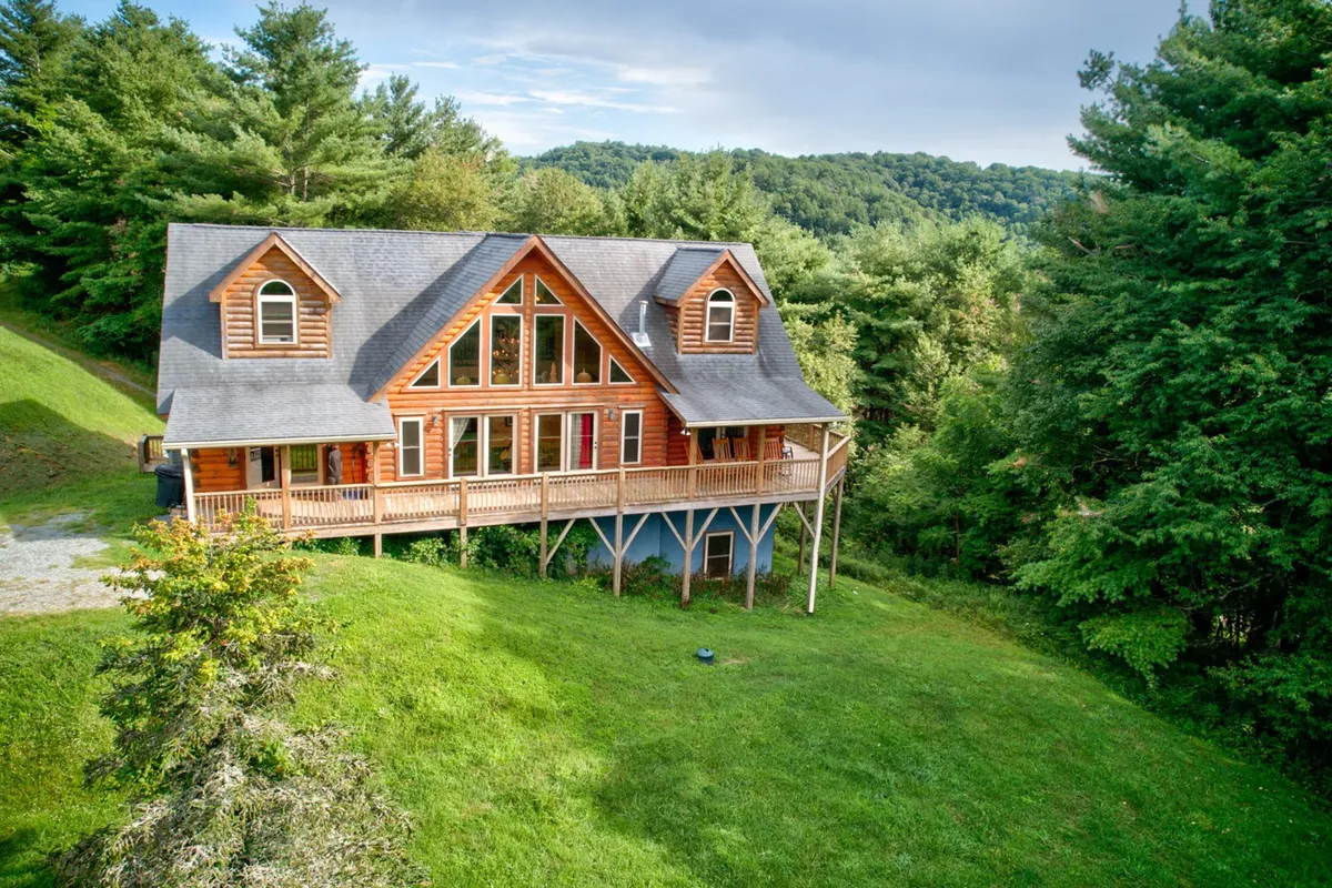 An exterior shot of the home’s wooden deck, backed by a lush forest and featuring large windows that connect indoor and outdoor spaces. The deck is set up for gatherings, barbecues, and stargazing—perfect for family fun and bonding.