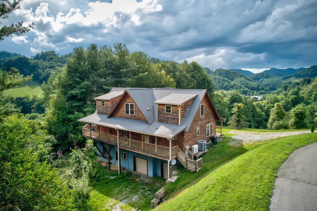 This image showcases a wooden cabin nestled among trees with a broad deck area and a beautiful mountain backdrop. The deck provides a space for families to relax outdoors, take in the views, or gather for activities together. The tranquil setting hints at a peaceful retreat after days spent exploring the High Country.