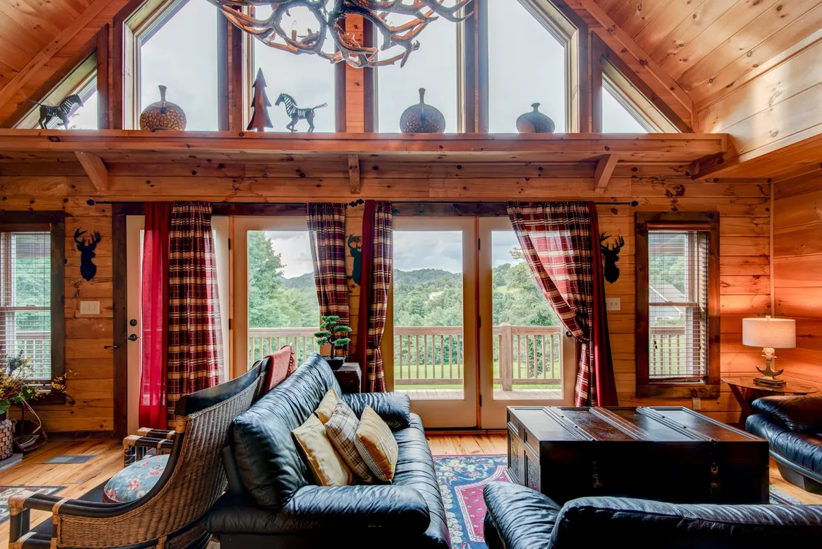 A bright, airy interior space with large windows framing scenic views, a comfortable seating area, and decorative touches. The room is ideal for watching sunsets or gathering with loved ones, evoking both warmth and connection to nature.