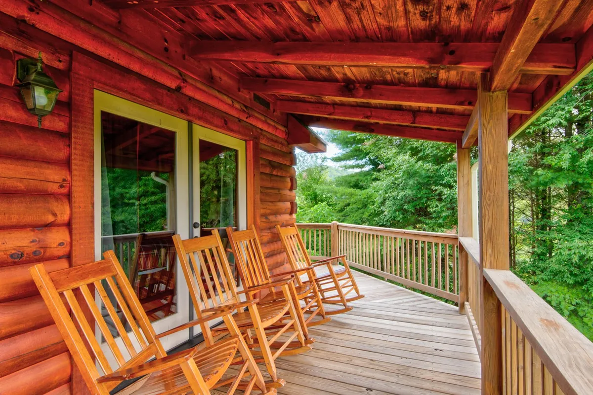 This image showcases the log cabin’s charming exterior, with inviting rocking chairs placed on the porch and enveloped by greenery. The tranquil mood and the setup of the porch suggest opportunities for morning coffee, birdwatching, and enjoying peaceful moments surrounded by nature.